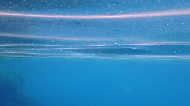 Κάτω από το νερό. επιφάνεια της θάλασσας. Κοντινό πλάνο. μπλε επιφάνεια καθαρού θαλασσινού νερού, φωτισμένη από τις ακτίνες του ήλιου, τις ακτίνες, την κίνηση, το κούνημα. Βίντεο αργής κίνησης — Αρχείο Βίντεο