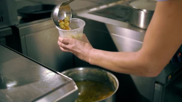 Donazioni. cucinare. beneficenza. consegna di cibo. Beneficenza, mense comunitarie servono pasti gratuiti a poveri e bisognosi. lo chef versa la zuppa calda in un contenitore alimentare. — Video Stock