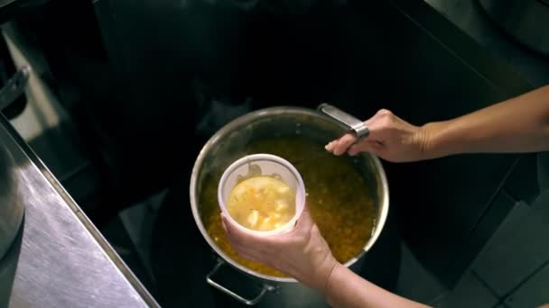 Donaciones. cocinar. caridad. comida a domicilio. Las organizaciones benéficas y los comedores comunitarios están sirviendo comidas gratis a los pobres y necesitados. el chef vierte sopa caliente en un recipiente de comida. — Vídeo de stock