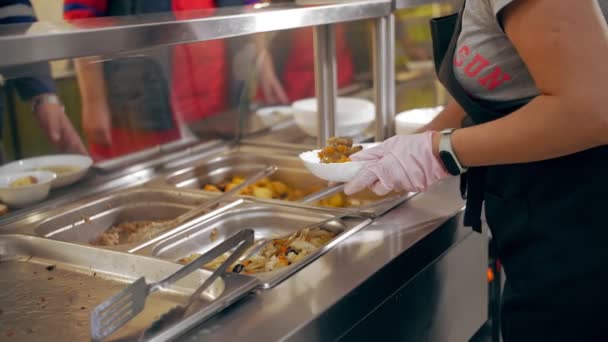 En bufférestaurang. Självbetjäningscafeteria. närbild. Servitrisen, i skyddshandskar, lägger mat på tallrik åt kunden. matlagning. hälsokost. — Stockvideo