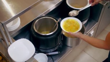 Açık büfe restoranı. Kendi kendine hizmet veren kafeterya. Yakın plan. Garson, koruyucu eldivenlerle müşteriye sıcak çorba dolduruyor. Yemek pişirmek. sağlıklı gıda.