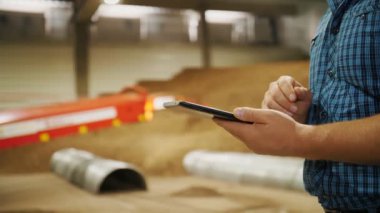 Depoda patates deposu var. Patates hasadı Yakın plan. Erkek eller dijital tablet kullanıyor, patates deposu ve teçhizat zeminine karşı. tarım.