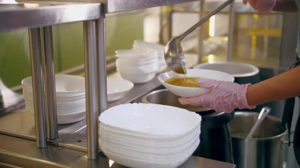 Buffet restaurant. Zelfbedieningscafetaria. close-up. serveerster, in beschermende handschoenen, giet hete soep in een kom voor de klant. koken. Gezondheidsvoedsel. — Stockvideo