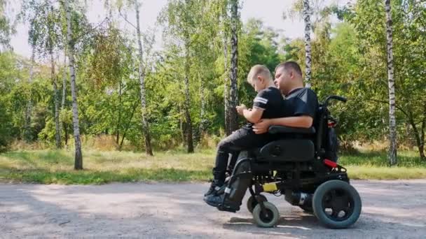 Día de los padres. Papá e hijo. Papá y su hijo pasan tiempo juntos, divirtiéndose. persona con discapacidad. personas con necesidades especiales. usuario de silla de ruedas. — Vídeo de stock