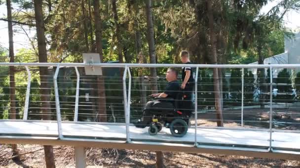 Babalar günü. Engelli biri. Babası ve küçük tatlı oğlu yaz günü parkta yürüyorlar. Babam tekerlekli sandalye kullanıcısı. Özel ihtiyaçları olan insanlar.. — Stok video