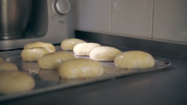 Yemek pişirmek. Fırın. Hamur tatlısı yapmak. Yakın plan. Çiğ hamur hamurlu turtalar, metal bir fırın tepsisine serilmiş, fırında pişirilmeye hazır. Turtalar yumurta sarısı ile kaplanmış.