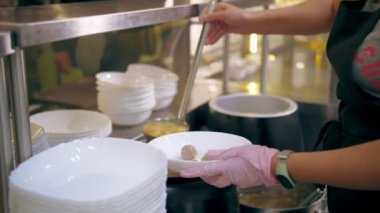 Açık büfe restoranı. Kendi kendine hizmet veren kafeterya. Yakın plan. Garson, koruyucu eldivenler içinde, müşteri için sıcak çorbayı kaseye dolduruyor. Yemek pişirmek. sağlıklı gıda.