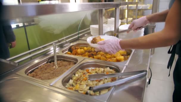 Buffet restaurant. Zelfbedieningscafetaria. close-up. serveerster, in beschermende handschoenen, zet eten op het bord voor de klant. koken. Gezondheidsvoedsel. — Stockvideo