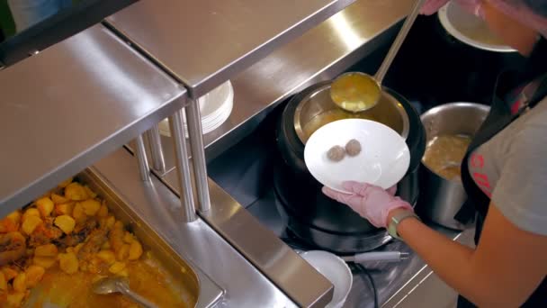 Açık büfe restoranı. Kendi kendine hizmet veren kafeterya. Yakın plan. Garson, koruyucu eldivenlerle müşteriye sıcak çorba dolduruyor. Yemek pişirmek. sağlıklı gıda. — Stok video