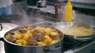 Yemek pişirmek. Güveç. Açık büfe restoran mutfağı. Yakın plan. Yemek kaynıyor, tencerede kaynıyor. Ticari bir mutfakta yemek hazırlamak ve pişirmek.