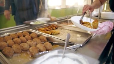 Açık büfe restoranı. Kendi kendine hizmet veren kafeterya. Yakın plan. Garson, koruyucu eldivenlerle, müşteriler için yemek hazırlıyor. Yemek pişirmek. sağlıklı gıda.