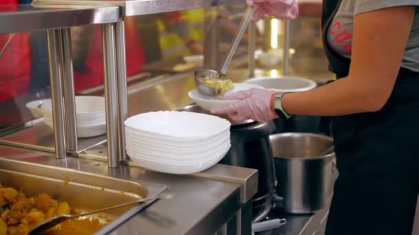 Açık büfe restoranı. Kendi kendine hizmet veren kafeterya. Yakın plan. Garson, koruyucu eldivenlerle müşteriye sıcak çorba dolduruyor. Yemek pişirmek. sağlıklı gıda. — Stok video