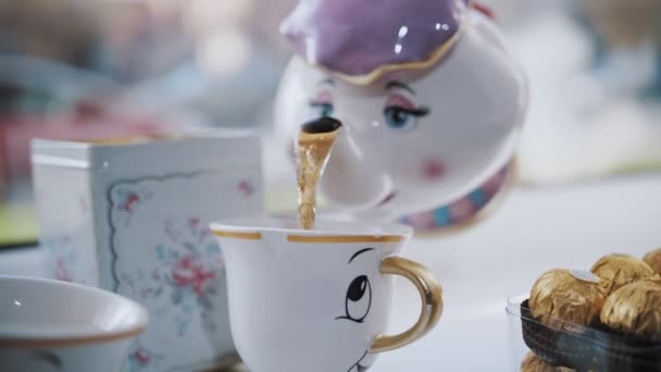 Tea party. primo piano. divertente set da tè per bambini. il tè caldo è versato in una tazza da una teiera. — Video Stock