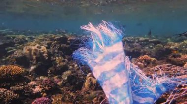 Denizde çöp. Denizin plastik kirliliği. Mavi plastik poşet güneş ışığında yavaşça suyun altında sürükleniyordu. Arka ışıklandırma. Plastik atık çevresel kirlilik sorunu