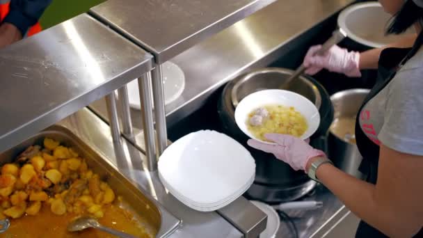 En bufférestaurang. Självbetjäningscafeteria. närbild. Servitris, i skyddshandskar, häller varm soppa i en skål för en kund. matlagning. hälsokost. — Stockvideo