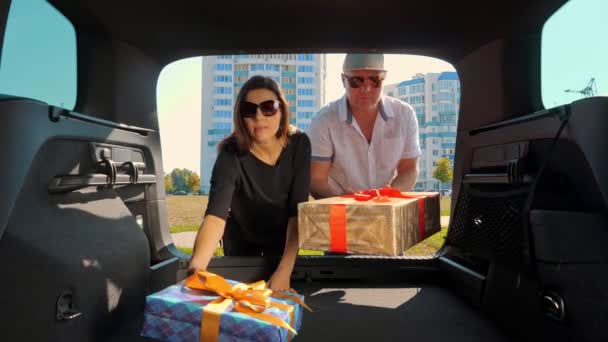 Delivery. donation, charity. gift boxes in car. man and woman load beautifully wrapped, packed boxes to car trunk. view from inside car. Online order. Christmas presents. — Stock Video