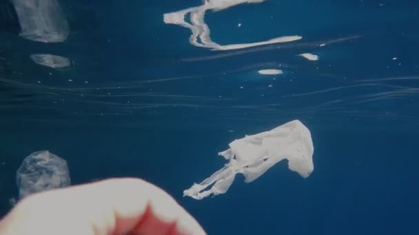 Garbage in the sea. clean up the sea. collect rubbish in water. close-up. male hand grabs waste, used plastic bags. first-person view. sea or ocean pollution. environment protection. — Stock Video