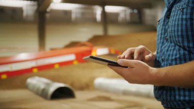 Depoda patates deposu var. Patates hasadı Yakın plan. Erkek eller dijital tablet kullanıyor, patates deposu ve teçhizat zeminine karşı. tarım.