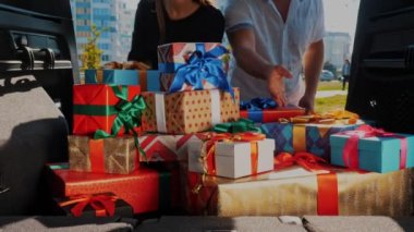 Teslimat. Bağış, bağış. Hediye kutuları arabada. Yakın plan. Kadın ve erkek, bagajdan güzelce paketlenmiş kutuları boşaltıyor. İçeriden görüntü. Noel hediyeleri. Çevrimiçi düzen.