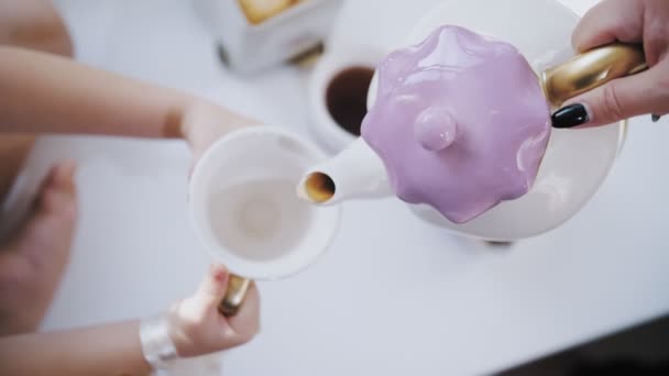 Tea party. primo piano. divertente set da tè per bambini. il tè caldo è versato in una tazza da una teiera. — Video Stock