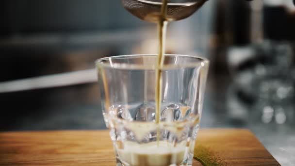 Matcha latte. Yakın plan. Barista, süzgeçten geçen süt ve kibrit yeşil çayı süzüyor. Kokteyl bardağa dökülür.. — Stok video