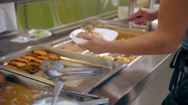 Açık büfe restoranı. Kendi kendine hizmet veren kafeterya. Yakın plan. Garson, koruyucu eldivenlerle, müşteriler için yemek hazırlıyor. Yemek pişirmek. sağlıklı gıda.