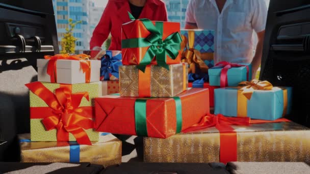 Entrega. donación, caridad. cajas de regalo en el coche. Primer plano. hombre y mujer descargar maravillosamente envuelto, cajas empacadas, del maletero del coche. vista desde el interior del coche. Regalos de Navidad. Pedido en línea. — Vídeo de stock