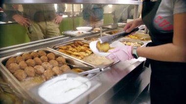 Açık büfe restoranı. Kendi kendine hizmet veren kafeterya. Yakın plan. Garson, koruyucu eldivenlerle, müşteriler için yemek hazırlıyor. Yemek pişirmek. sağlıklı gıda.