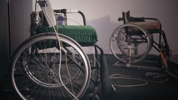Atleta discapacitado. Esgrima. Juegos paralímpicos. cerca de silla de ruedas. sillas de ruedas especiales, fijador eléctrico y otros equipos para el entrenamiento de esgrima de atletas discapacitados en sillas de ruedas, en el gimnasio. — Vídeo de stock