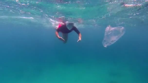 Odpadky v moři. Dobrovolník, dívka teenager, v šnorchlovací masce, sbírá plovoucí odpadky nad korálovým útesem, unášené plastové sáčky. znečištění moře nebo oceánu. ochrana životního prostředí. — Stock video