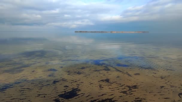 水の中の反射。風景だ。雲のある青空は、川や湖の透明な表面に反映されます。海岸近くの澄んだ水の中に砂の底が見えます。早春. — ストック動画