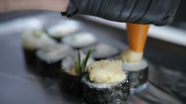 Suşi. Japon yemeği. Yemek pişirmek. Mutfak. Suşi şefi krem peynirli suşi ruloları yapıyor, salatalık malzemeleri, pirinç, Norveç yosunu. Yakın plan. Restoranın mutfağında..