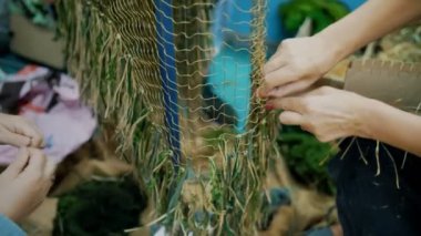 Kamuflaj ağı. Gönüllüler askeri insanlar için yeşil haki kumaş parçalarından bir kamuflaj pelerini örüyorlar. Ukrayna 'da savaş. Gönüllü. Çatışmalar sırasında koruma