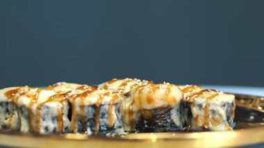 Suşi. Japon yemeği. Yakın plan. Siyah tabakta servis edilen taze pişmiş suşi ruloları dönüyor. Yemek pişirmek. Mutfak. Asya yemekleri.