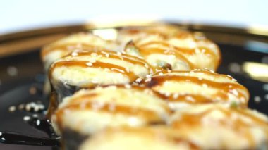 Suşi. Japon yemeği. Yakın plan. Siyah tabakta servis edilen taze pişmiş suşi ruloları dönüyor. Yemek pişirmek. Mutfak. Asya yemekleri.