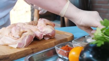 Chicken. cooking. close-up. Chef is sprinkling, rubbing a fresh raw chicken with spices and salt on a cutting board. Chef cooks chicken for baking