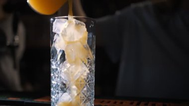 cocktail. making cocktail. bartender makes cocktail. close-up. Bartender pours an Orange fresh into a glass with ice on bar counter. cocktail of different ingredients.