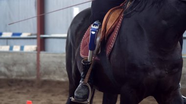 yakın çekim, yapay bacak, bacak stirrups içinde. Erkek binici, bacak, olmadan Engelli kişi ata, hippoterapi binmek öğrenir. hayvanlarla Engelli rehabilitasyonu kavramı
