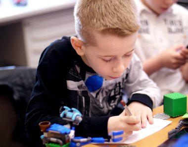 the boy of 10 years, draws a drawing, a project of a robot model, a machine, plays in the designer from cubes, plates, circuits, wires. he is fond of robotics, programming, modeling,. High quality