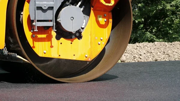 close-up, Road construction works with roller compactor machine , asphalt finisher. Road roller laying fresh asphalt pavement on top of the gravel base during road construction. High quality photo