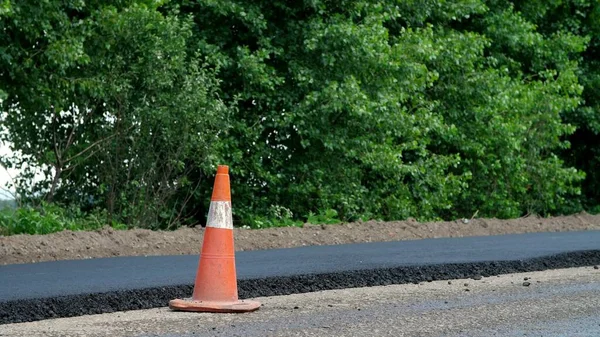 Traffic Cone on road. Road construction works , road repair. On the road there is fresh asphalt laid on one side of the traffic. Construction and repair of highway. High quality photo