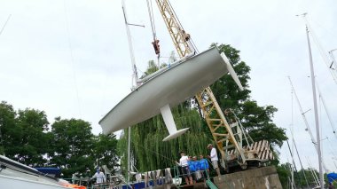 KYIV, UKRAINE, YACHTING-JULY 29, 2018: on the Dnieper River shore, on pier, lifting crane raises white yacht, man in special clothes, with special mop, machine washes the yacht. High quality photo