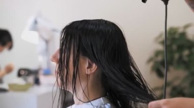 Saç kurutma. Kuru saç. Yakın plan. Kuaför, kuaför kuaföründe saç kurutma makinesi kullanarak, yıkadıktan sonra müşterinin saçını kurutuyor.