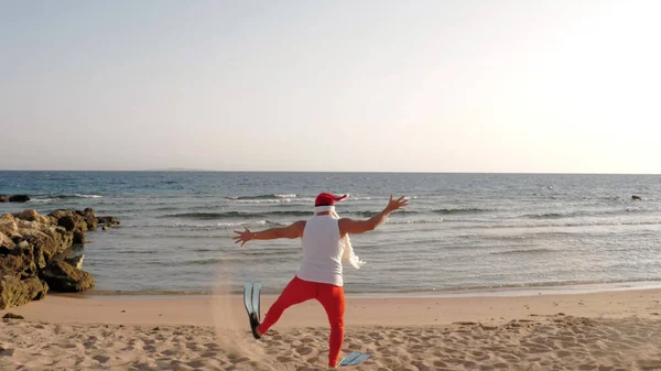 클로스의 아버지 크리스마스 재미있는 산타클로스는 물갈퀴를 가지고 모래사장을 바다로 수영을 — 스톡 사진