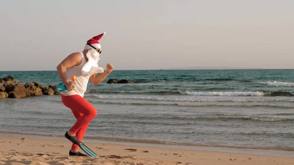 Santa Claus summer vacation. Santa Claus having fun. Funny Santa, in sunglasses and flippers, is dancing on beach by the sea and relaxing. Santa going to snorkel. High quality photo