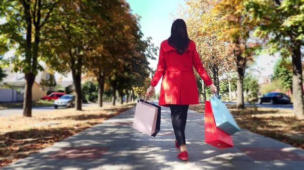 Woman with shopping bags. Back view. woman, in protective mask, with colored shopping bags in her hands, walking through city alley. shopping and gifts. delivery or donation concept. High quality