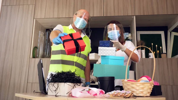 delivery service for parcels, gifts. courier wears protective mask. designer, in mask, packs gift bag. home delivery due coronavirus pandemic. online sales, online shopping. High quality photo