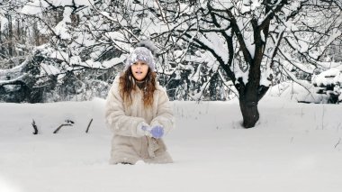Karlı kış eğlencesi. Kartopu yapmak. Sıcak kış kıyafetleri giymiş mutlu, sevimli, güzel kız, kar topu yapıyor, dışarıda eğleniyor, karlı kış gününde, parkta ya da ormanda. Yüksek kalite fotoğraf