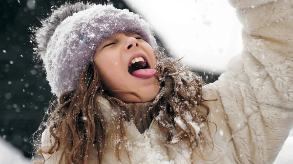 冬の家族の楽しみ 雪の結晶を舌でキャッチ 雪の冬の日に楽しむ雪と雪の日を楽しんで かなり小さな女の子は彼女の舌で雪の結晶をキャッチしています スローモーション ストックフォト