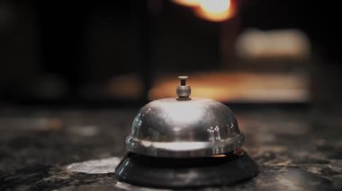 Silver Bell 'i ara. Yakın plan. Restoran barındaki tezgahın üstünde servis ziline basar.